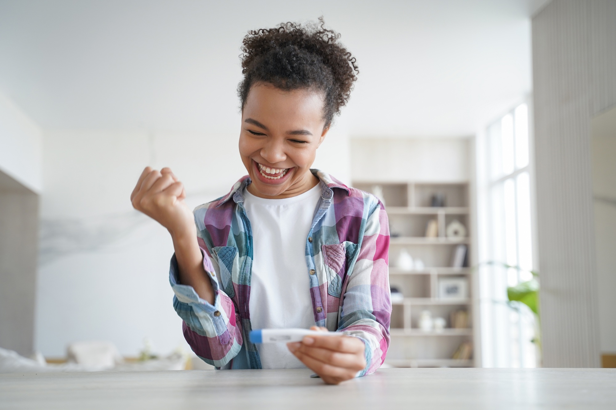 Happy african american teenage girl gets negative pregnancy test result. Contraception concept.