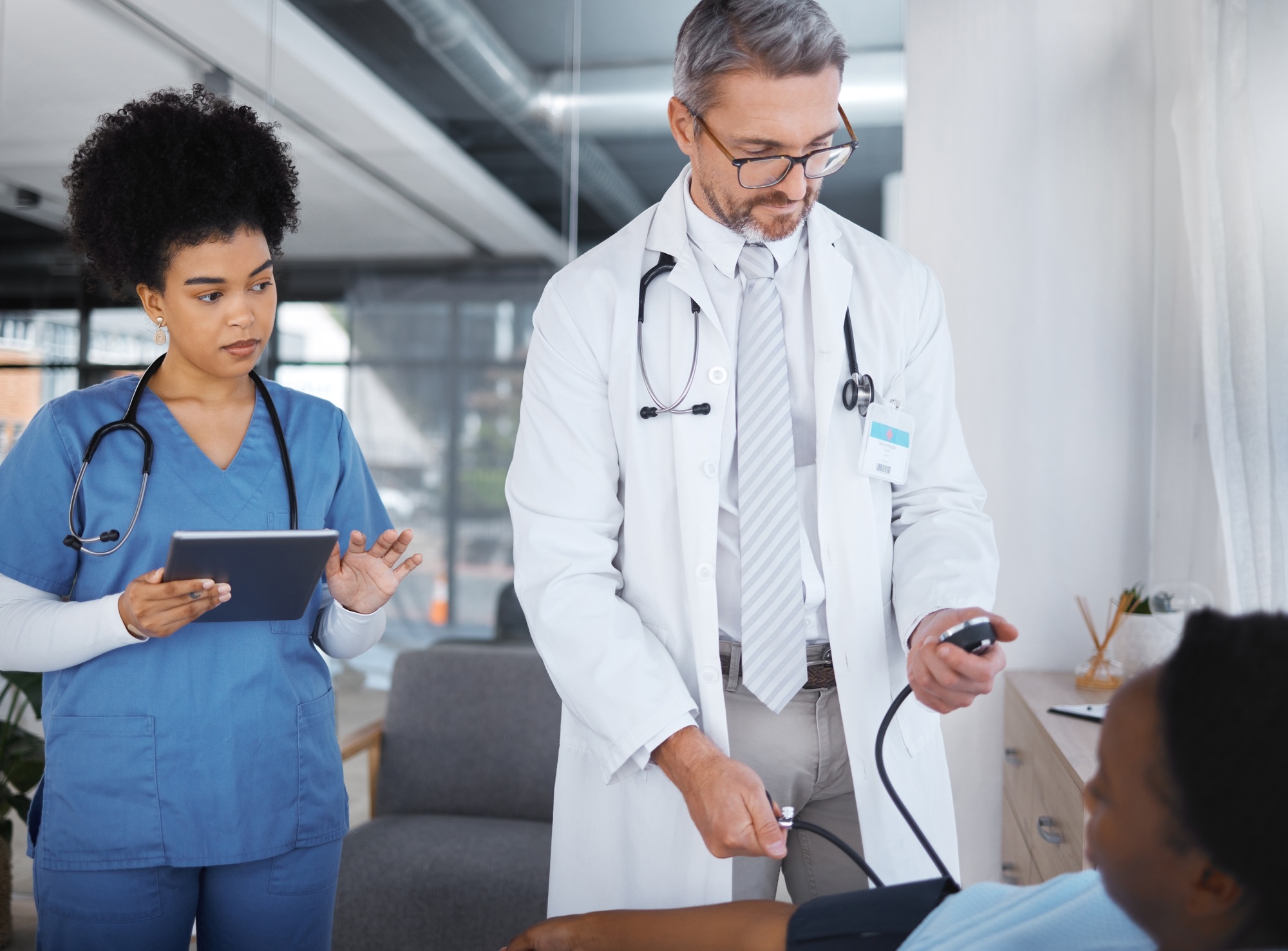Doctor, patient and blood pressure in clinic with nurse, tablet and analysis for teamwork, health o