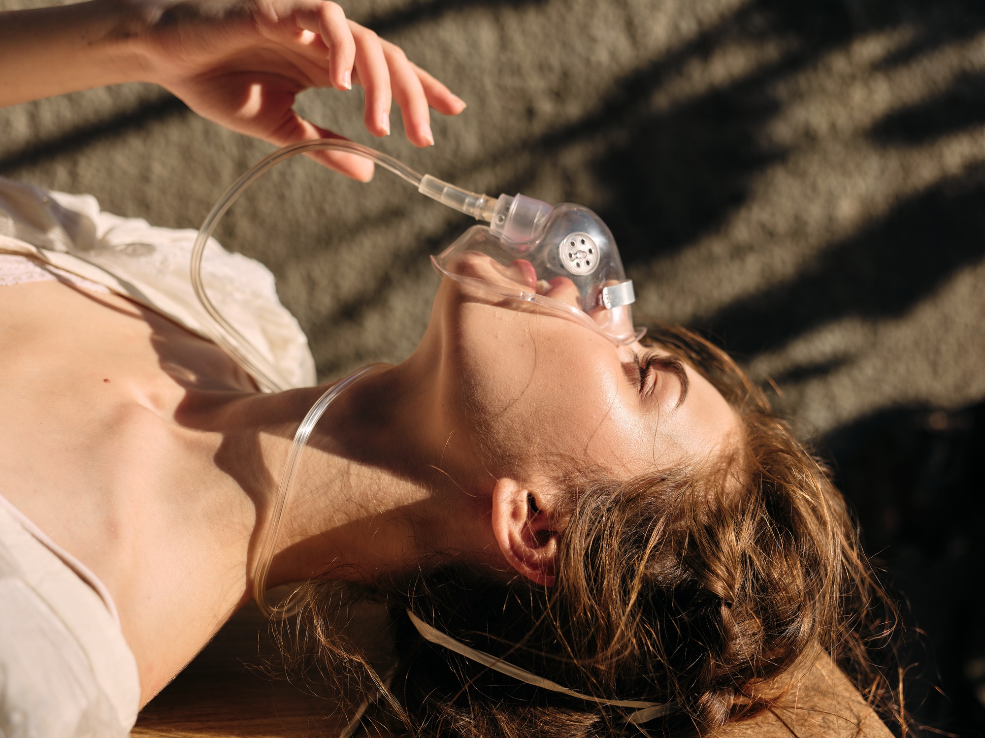 Woman lying on ground with oxygen mask and inhaler, receiving medical treatment for respiratory